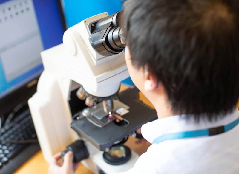 Trainee pathologist looking into microscope